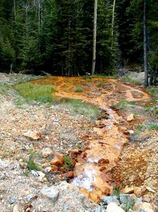 Photograph showing iron oxide deposition in stream near abandoned mining operation.